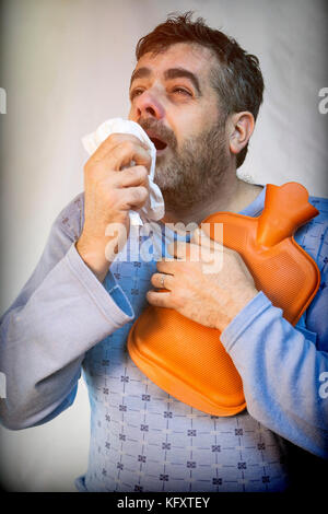 Mann mittleren Alters im Schlafanzug Niesen mit einer starken Erkältung Stockfoto