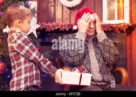 Adorable Little Boy gibt ein Weihnachtsgeschenk zu seinem Großvater Stockfoto