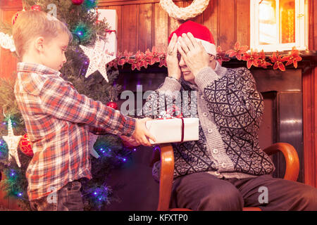 Adorable Little Boy gibt ein Weihnachtsgeschenk zu seinem Großvater Stockfoto