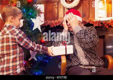 Adorable Little Boy gibt ein Weihnachtsgeschenk zu seinem Großvater Stockfoto