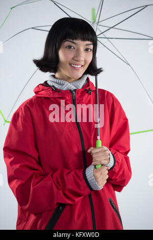 Lächelnde Frau in roter Jacke Holding einen Regenschirm Stockfoto