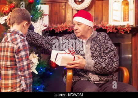 Adorable Little Boy gibt ein Weihnachtsgeschenk zu seinem Großvater Stockfoto