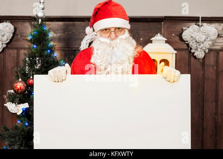 Santa claus zeigt eine leere Plakatwand in Ihrem Haus Stockfoto