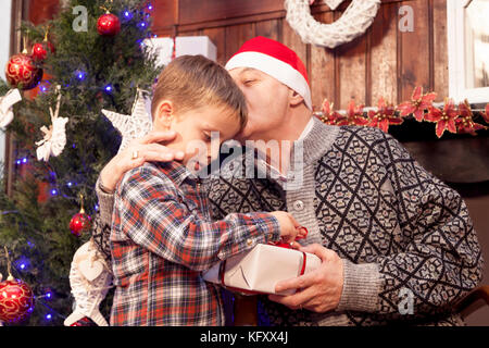 Adorable Little Boy gibt ein Weihnachtsgeschenk zu seinem Großvater Stockfoto