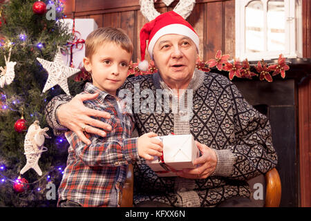 Adorable Little Boy gibt ein Weihnachtsgeschenk zu seinem Großvater Stockfoto