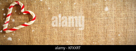 Schnee gegen herzförmige Zuckerstange auf Auf Gewebe Stockfoto