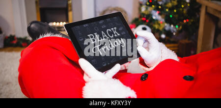 Schwarzer Freitag gegen Santa Claus sitzt und mit Hilfe von digitalen Tablet Stockfoto
