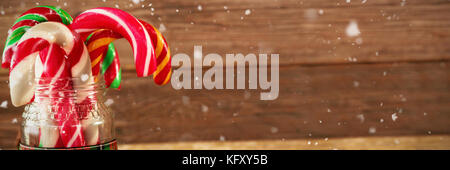 Schnee gegen Tannenzapfen und Candy Cane in den jar gegen Holzbrett Stockfoto