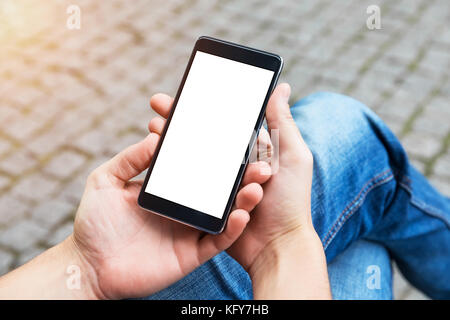 Mann nutzt sein Handy im Freien, Nahaufnahme. Bild von jungen Mann mit Handy auf der Bank sitzen. Stockfoto