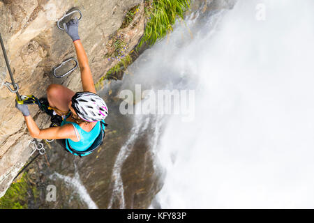 Eine weibliche Bergsteiger von einem Felsen über dem stuibenfall in Österreich hängen Stockfoto