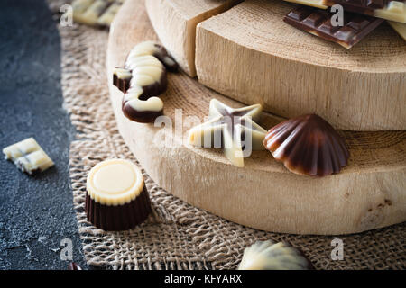 Verschiedene rohe Schokolade Bonbons auf Holzbrett, dunklen Hintergrund. Gesunde Süßigkeiten Stockfoto