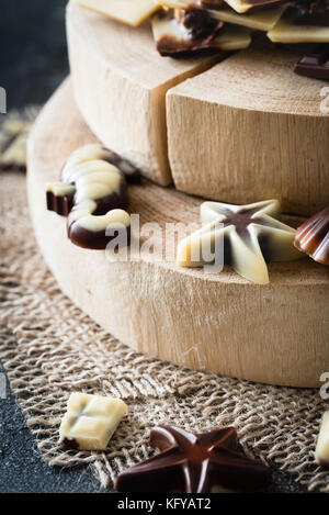 Verschiedene rohe Schokolade Bonbons auf Holzbrett, dunklen Hintergrund. Gesunde Süßigkeiten Stockfoto
