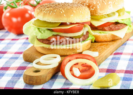 Konzept Bild der traditionelle hausgemachte Hamburger mit Rindfleisch, Salat, Käse, Tomaten und Gurken auf Holzbrett. Stockfoto