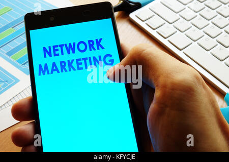 Hand Smartphone mit Worten Network Marketing. Stockfoto