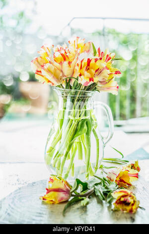 Schöne Tulpen Bündel in Glas Vase mit Wasser am Tisch am Frühling Tag Hintergrund, Vorderansicht Stockfoto