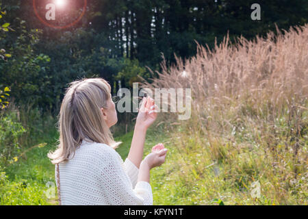 Das Mädchen macht einen Wunsch und bläst nach unten. Stockfoto