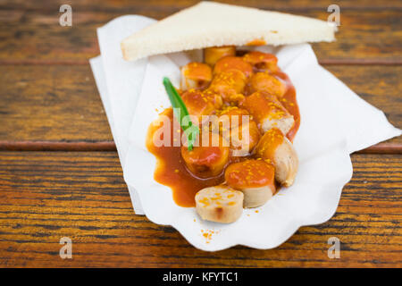 Deutsche currywurst Bratwurst mit Soße und Brot auf einem Holztisch Stockfoto
