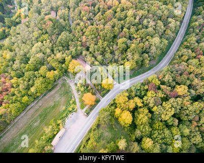 Straße durch den Wald mit Herbstfarben. Luftaufnahme. Stockfoto