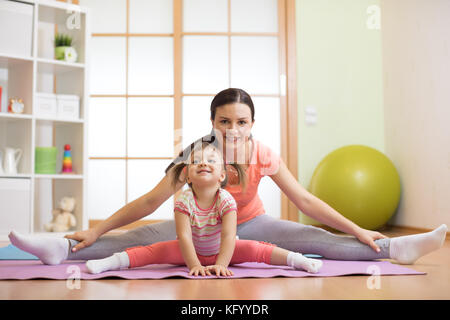 Mutter und Tochter tun Fitness Übungen auf der Matte zu Hause Stockfoto