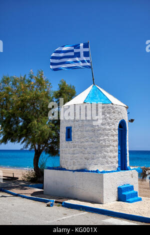 Die griechische Flagge auf dem Dach des redundanten Windmühle in der Griechischen Nationalen Farben blau lackiert und an stagna Strand weiß, Archangelos, Rhodos, Griechenland Stockfoto