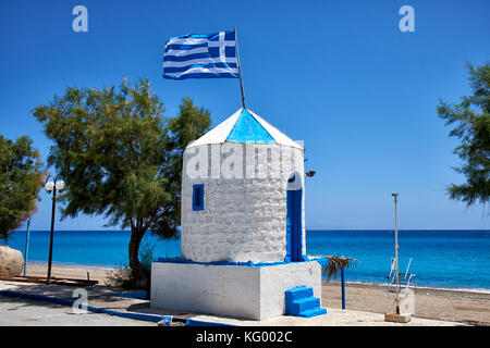 Die griechische Flagge auf dem Dach des redundanten Windmühle in der Griechischen Nationalen Farben blau lackiert und an stagna Strand weiß, Archangelos, Rhodos, Griechenland Stockfoto