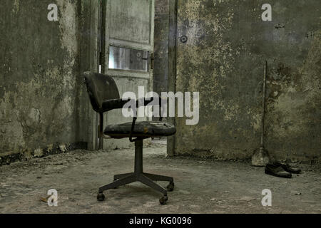 Ein furchtsames geschossen von einem Stuhl in der Dunkelheit, in einem Raum eines verlassenen psychiatrischen Krankenhaus, mit einem unheimlichen Umgebung. Stockfoto