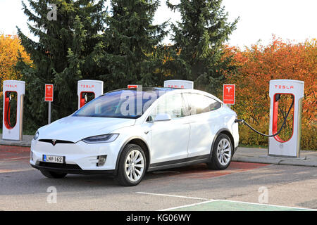 PAIMIO, Finnland - 15. OKTOBER 2017: Weiße Tesla Model X elektrische Crossover-SUV Gebühren Batterie bei Tesla Kompressor station in Paimio. Stockfoto