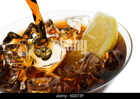 Gießen Cola in Glas mit Eiswürfeln und Zitrone in Scheiben schneiden, auf weißem Hintergrund Stockfoto