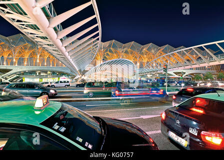 Autos und Taxis bewegen sich nachts vor futuristischer Stahldachkonstruktion Stockfoto