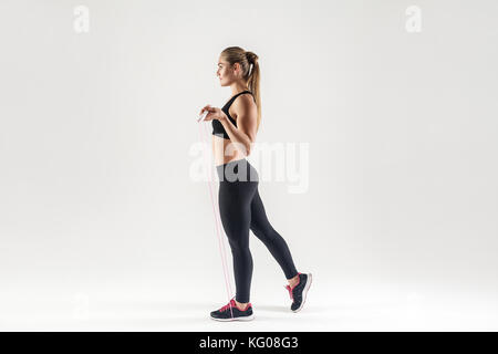 Seitenansicht. attraktive Frau mit Springseil und freuen uns. studio Shot, grauer Hintergrund Stockfoto