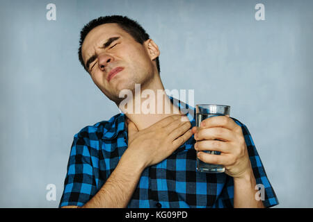 Portrait man Husten, drücken auf der Brust mit schmerzhaften Ausdruck. Schmerz und Halsschmerzen während der Krankheit der Influenza. Der Mann hält ein Glas wat Stockfoto