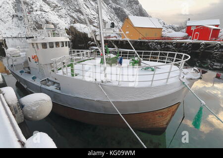 Schnee bedeckt Hafen - Fischerdorf nusfjord - alten hölzernen Fischerboot - bottelvika Bucht - nesheia+sultinden Mounts - Rot + orange Fischerhütten oder Rorbuer fo Stockfoto