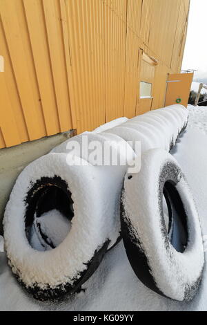 Alte gelbe Holz- port Warehouse - Reihe alter Reifen für pneumatische Kotflügel - dock Stoßfänger auf der Landungsbrücke - Pier auf der n. Seite der Fischerei Stockfoto