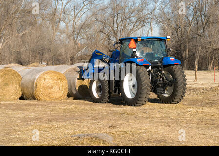 New Holland T6030 Traktor herauf runde Heuballen mit neuen 840Tl Frontlader auf einer Ranch Stockfoto