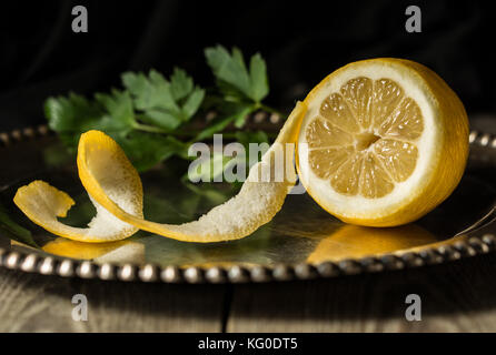 Die Hälfte frische Zitrone auf einem Silbertablett mit grüne Kräuter im Hintergrund geschält Stockfoto