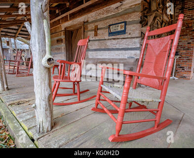 Altmodische weiße Schaukelstühle auf der Veranda eines alten Hütte in ländlichen Alabama, USA. Stockfoto