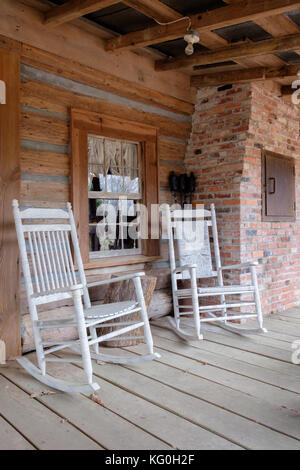 Altmodische weiße Schaukelstühle auf der Veranda eines alten Hütte in ländlichen Alabama, USA. Stockfoto