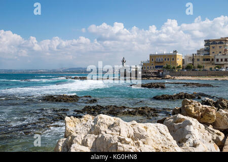 Steine und das blaue Meer an der Küste von Reifen mit Leuchtturm in Reifen, Sauer, Libanon Stockfoto