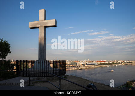 Steinkreuz Denkmal oberhalb der Höhle Kirche auf Gellert Hügel mit Blick auf die Stadt und die Donau in Budapest, Ungarn Stockfoto