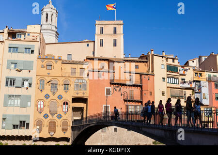 Eine Gruppe von Mädchen überqueren Sie eine Brücke über den Fluss Onyar mit dem historischen Häusern in der Altstadt von Girona, Katalonien, Spanien im Hintergrund. Stockfoto