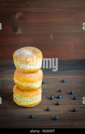 Blueberry Krapfen mit Puderzucker bestreut auf Holz- Hintergrund. Stockfoto