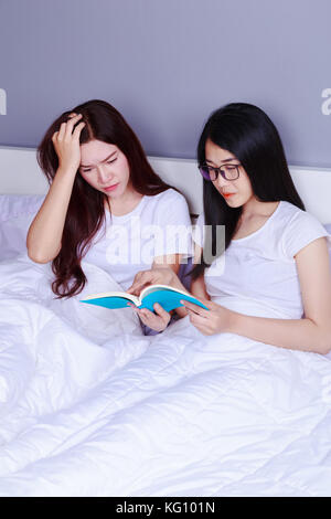 Zwei Frau mit einem Buch auf dem Bett im Schlafzimmer Stockfoto