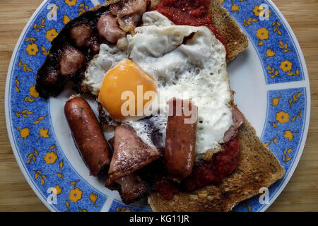 Frühstück mit geräuchertem Speck, Würstchen, Spiegeleier und Braun grunchy Toast Stockfoto