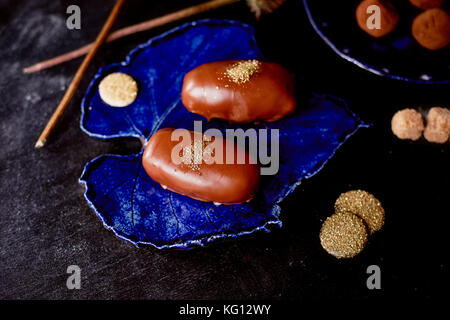 Schokolade Kartoffel Kuchen mit gold Pulver auf den tiefen blauen Platte. Eine Arbeit der kulinarischen Kunst Stockfoto