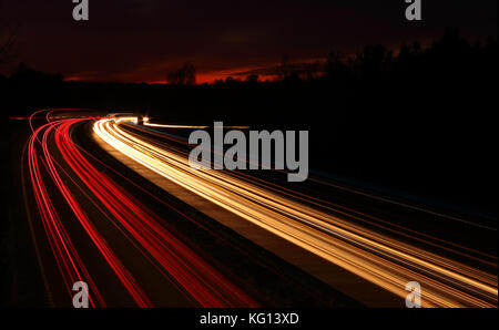 Auto Licht trails Nachts auf der Autobahn im Sonnenuntergang Stockfoto