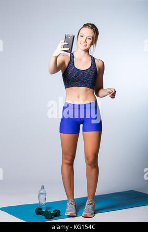 Weibliche fitness Modell Ausruhen nach einem intensiven Training und nehmen einige ein selfie im Spiegel der Fitnessraum. Stockfoto