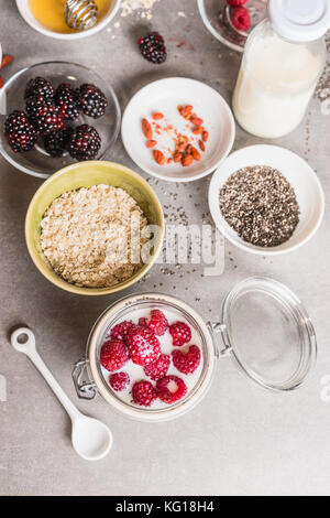 Gesundes Frühstück in Glas mit Haferflocken, Chia Samen, Goji Beeren, frische Beeren und Joghurt, Ansicht von oben Stockfoto