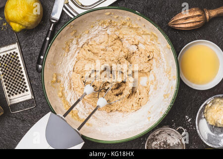 Mischen Teig mit der Hand Mixer am Küchentisch Hintergrund mit Zutaten zum Kochen, Ansicht von oben Stockfoto