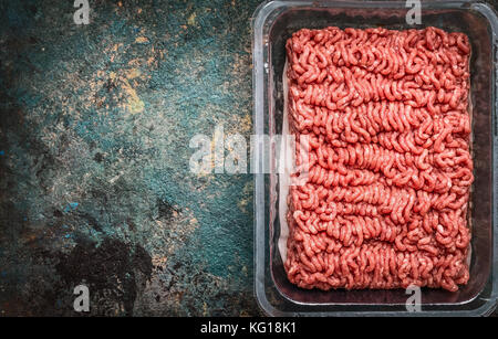 Rohes Hackfleisch in Kunststoffbox auf rustikalen Hintergrund, Ansicht von oben, Platz für Text Stockfoto