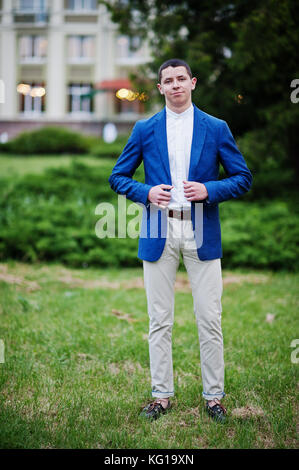 Porträt von einem gutaussehenden jungen Mann in coolen Anzug posiert auf dem Rasen auf seiner prom Tag gekleidet. Stockfoto